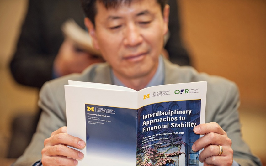 Man reading a Center on Finance, Law & Policy and OFR sponsored conference program