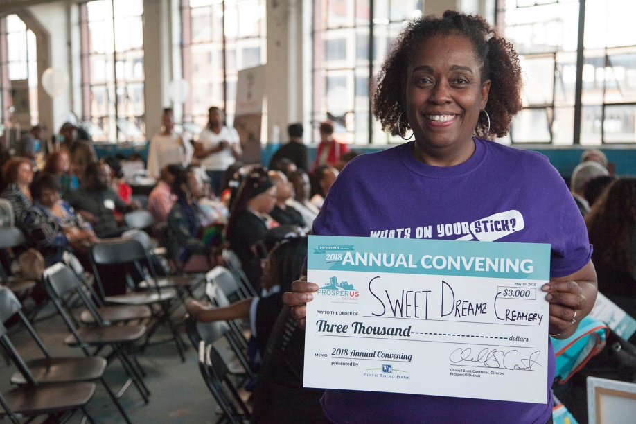 Sweet Dreamz Creamery owner holding up oversized check made out to the business