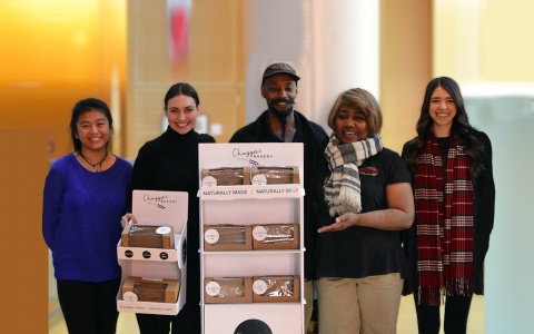 Group of students standing with Chuggas Bakery owners, holding a product display